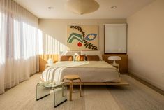 a bedroom with a bed, two stools and a painting on the wall