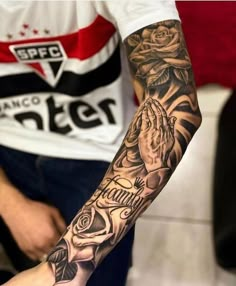 a person with a tattoo on their arm and hand holding a praying hands in front of him