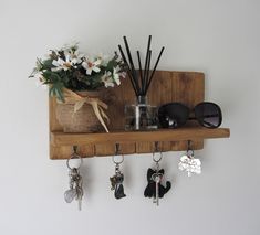 a wooden shelf with key hooks, sunglasses and flowers on the top is holding various items