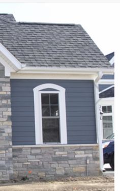 a blue house with white trim and windows in the front yard is being built by someone