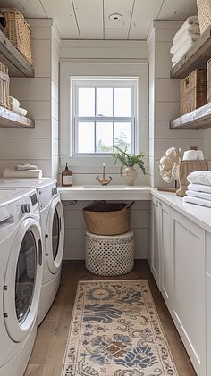 a washer and dryer in a white laundry room with open shelving on the wall