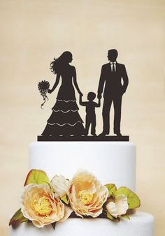 a wedding cake topper with a silhouette of a bride and groom holding the hand of a child