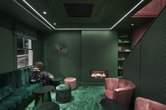 a living room with green walls and pink velvet sofas in front of a fireplace