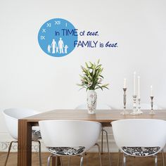 a dining room table with white chairs and a blue clock on the wall behind it