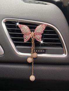 a car dashboard with a pink butterfly decoration hanging from it's center console