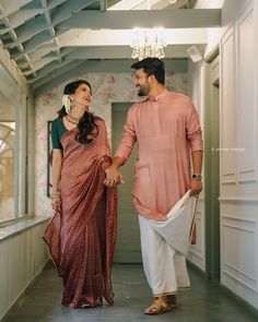 a man and woman holding hands walking down a hallway