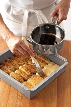 a person with a brush in their hand and some food on a pan next to them