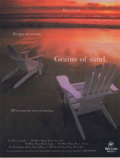 two white chairs sitting on top of a sandy beach next to the ocean at sunset