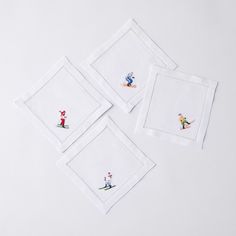 three white napkins with embroidered images on them