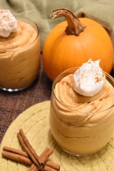 two pumpkin desserts with whipped cream and cinnamon sticks on the side, one in a glass bowl