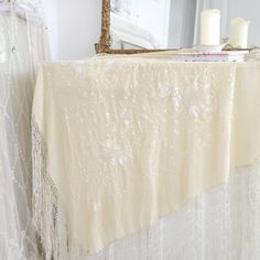 a table covered in white lace next to a mirror