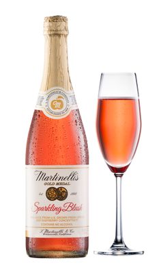 a bottle of sparkling wine next to a glass filled with pink liquid and ice cubes