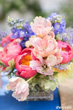 a vase filled with lots of pink and purple flowers on top of a blue table