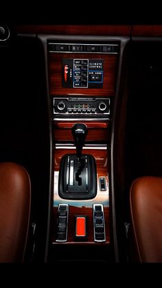 the interior of a car with an automatic gear box and dashboard controls, including two brown leather seats