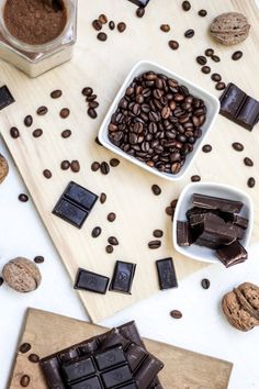 two bowls filled with chocolate next to some cookies and coffee beans on a cutting board