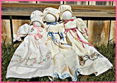 two dolls are sitting on the grass next to a wooden bench with pink border around them