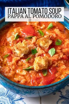 a blue bowl filled with tomato soup on top of a table