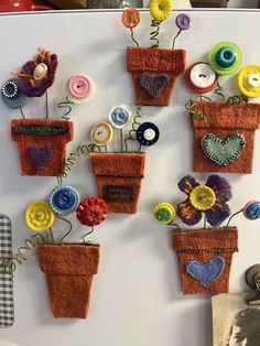 there are many small potted plants made out of buttons on the refrigerator magnets