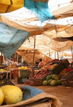 there are many fruits and vegetables on display under the awnings in this market