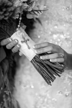 a woman holding a bouquet with flowers and a cross on it's arm, in black and white