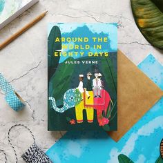 there is a book about the world in eighty days on top of a table with other items