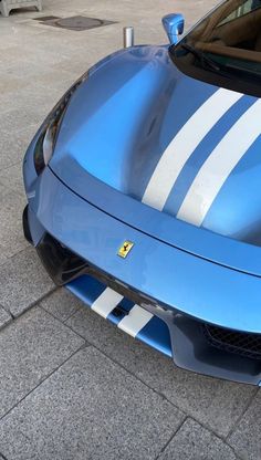 a blue sports car with white stripes parked on the street