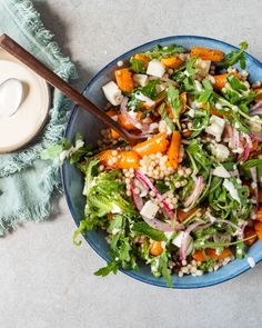 a salad with carrots, lettuce and other vegetables in a blue bowl