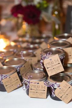 several small jars with labels on them sitting on a table next to candles and flowers