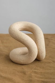 a white sculpture sitting on top of a wooden table next to a brown cloth covered floor