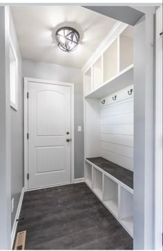 a white entryway with built in benches and storage cabinets on either side of the door