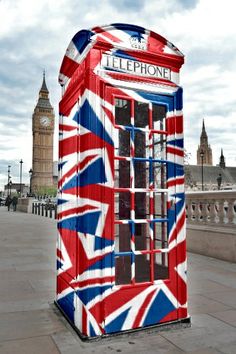 a phone booth painted like the british flag with big ben in the backgroud