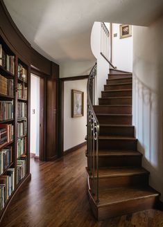 a spiral staircase with bookshelves in the corner and wooden floors on both sides