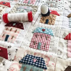 a close up of a quilt on a table with sewing needles and spools