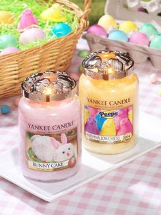 two yankee candles are sitting on a plate next to an easter basket and some eggs