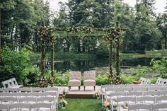 an outdoor ceremony setup with white chairs and greenery