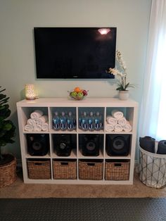 a tv mounted on top of a white shelf filled with lots of bottles and glasses