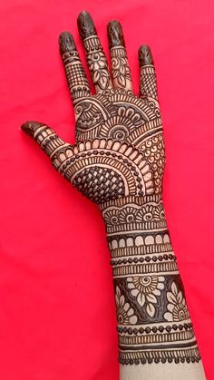 a hand with henna on it is shown against a pink background and red backdrop