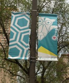 two banners hanging from a street light pole