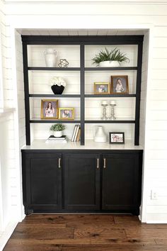 a black and white bookcase with some pictures on the top, shelves below it