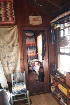 the inside of a cabin with wooden floors and walls covered in blankets, rugs, and other items