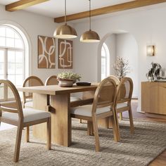 a dining room table and chairs with an area rug in front of the window that has arched windows