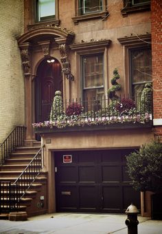 a fire hydrant sitting in front of a building with flowers on the balconies