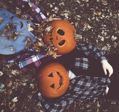 two pumpkins sitting on the ground with faces carved into them