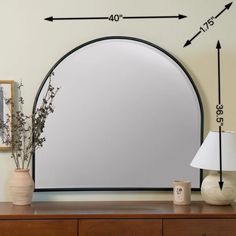 a mirror sitting on top of a wooden dresser next to a vase with flowers in it