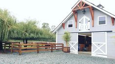 a barn with an open door and two horses standing in the front yard next to it