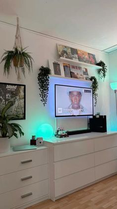 a living room with a large flat screen tv mounted to the wall and plants on top of it