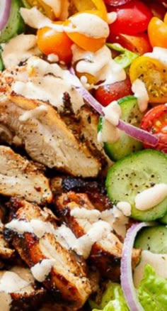 a salad with chicken, tomatoes, cucumbers and dressing