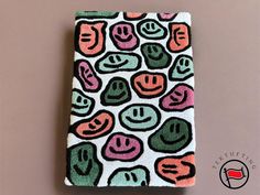 a small wallet with different colored faces on it's front and back cover, sitting on a table