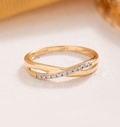 a gold ring with two diamonds on the top and bottom, sitting on a white surface