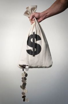 a hand holding a bag full of coins with a dollar sign hanging from it's side